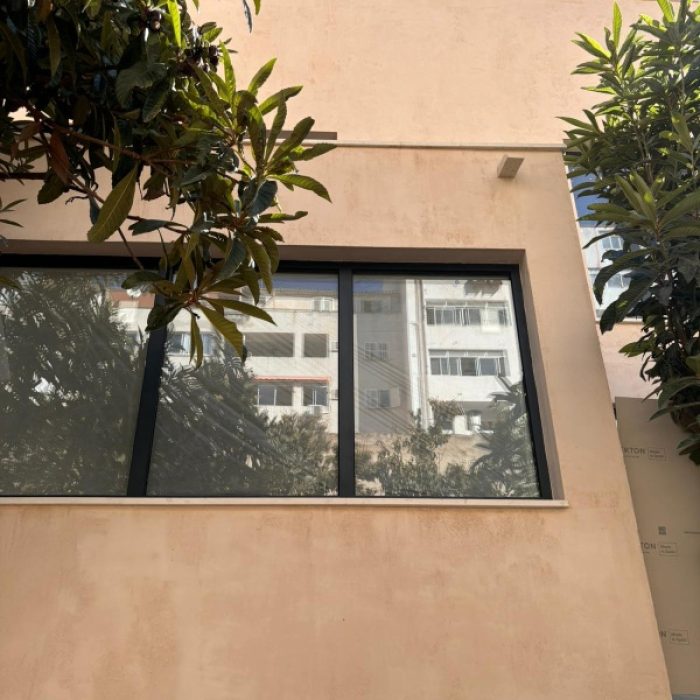 Minimalist modern villa exterior facade with a soft pinkish beige Chukum mineral coating behind a tree.