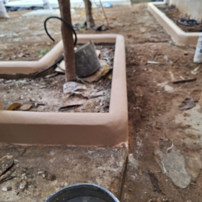Landscaped backyard garden surrounded by continuous earthy Chukum-coated perimeter walls.