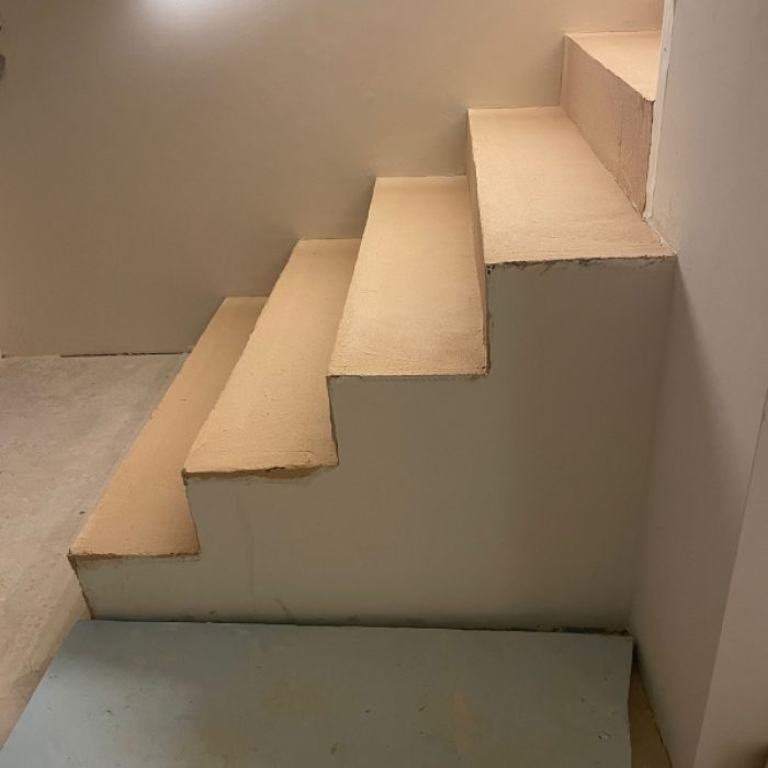 Interior staircase installation featuring smooth, warm-toned Chukum microcement steps under construction.