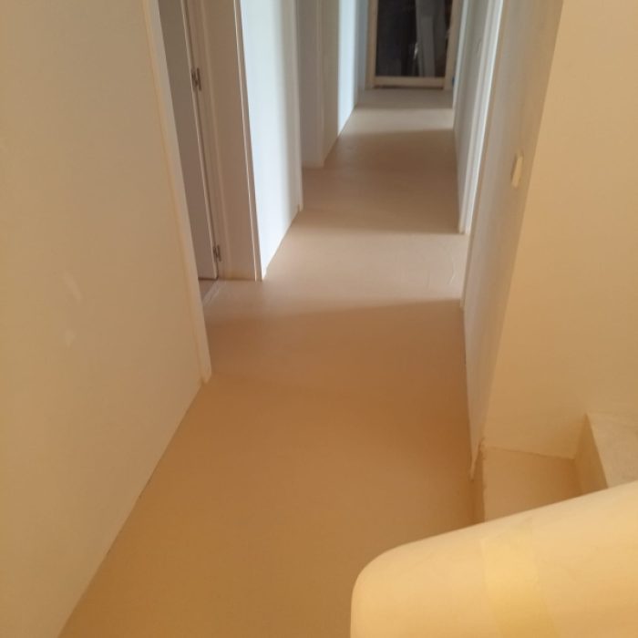 Interior staircase installation featuring smooth, warm-toned Chukum microcement steps under construction.