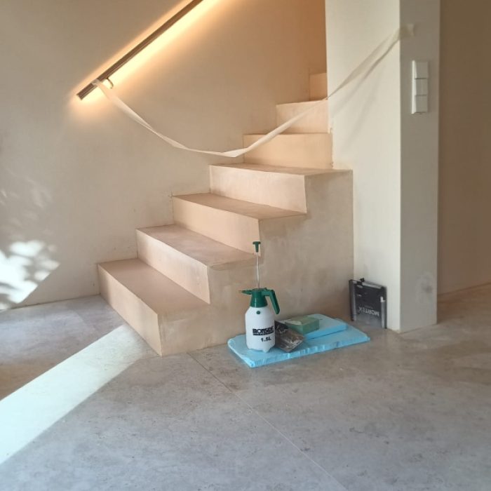 Interior staircase installation featuring smooth, warm-toned Chukum microcement steps under construction.