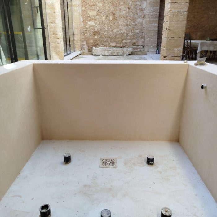 High-angle view of a custom-built swimming pool coated in beige Chukum microcement inside an Alcudia patio.