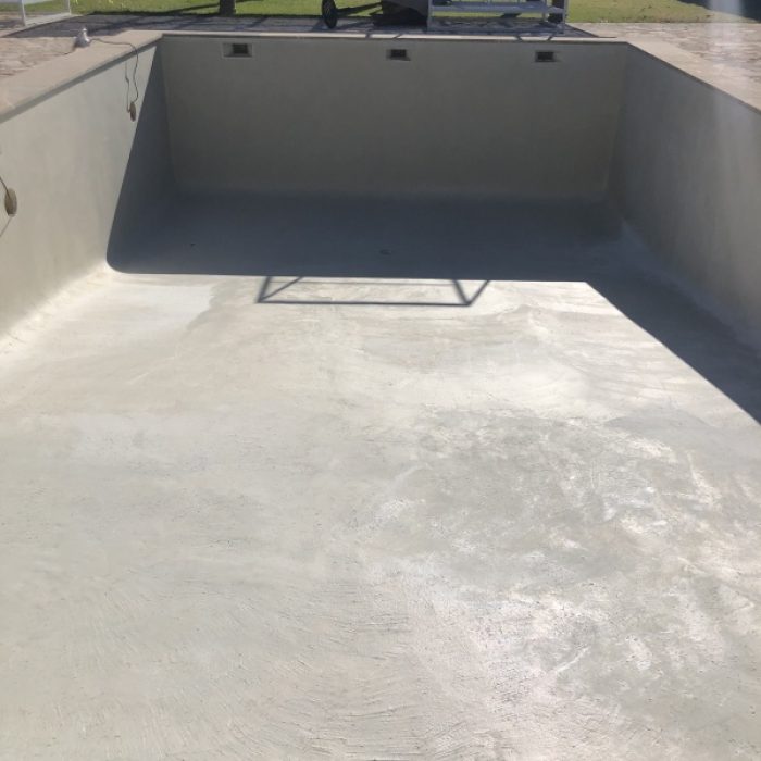 Empty countryside swimming pool showing the subtle textured patterns of a handcrafted Marblepool base before filling.