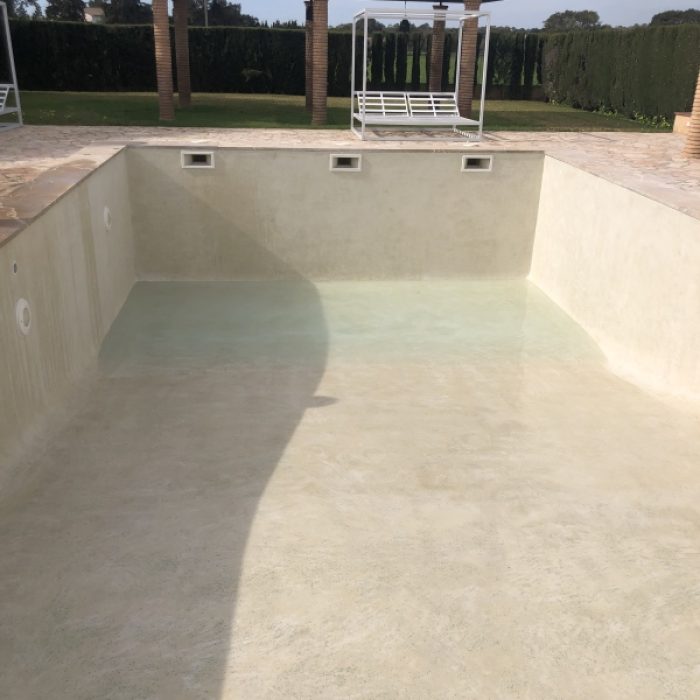 Wide perspective of a large rectangular swimming pool in Llubí with a continuous light grey Marblepool coating.
